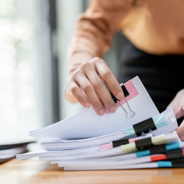 Businesswoman,Hands,Working,In,Stacks,Of,Paper,Files,For,Searching